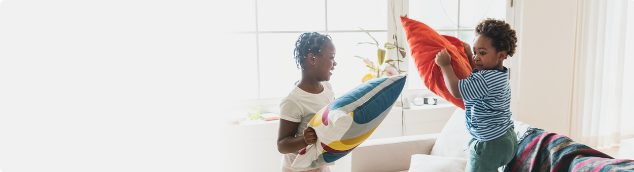 Two young children holding pillows